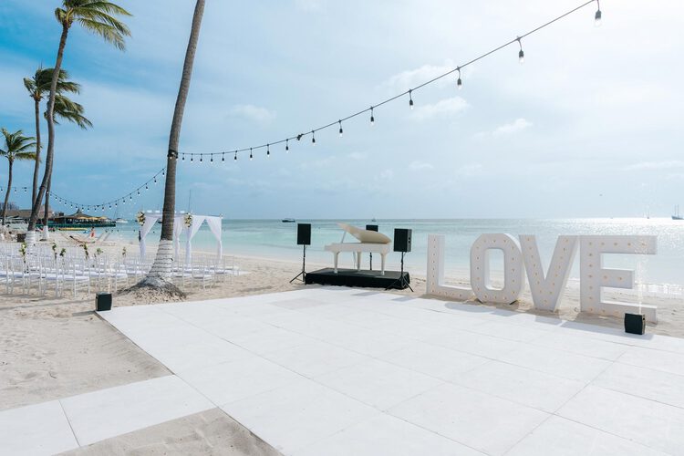 Un escenario de boda montado en la playa con un piano.