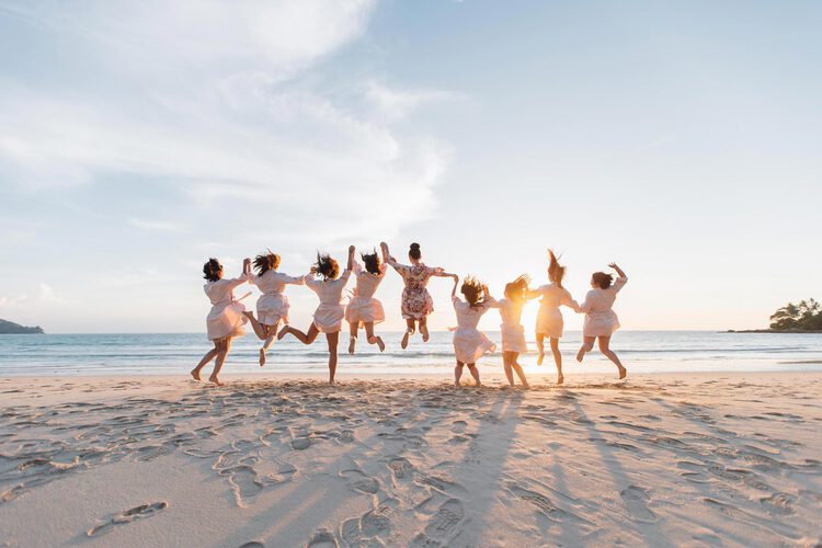 Damas de honor saltando en la playa