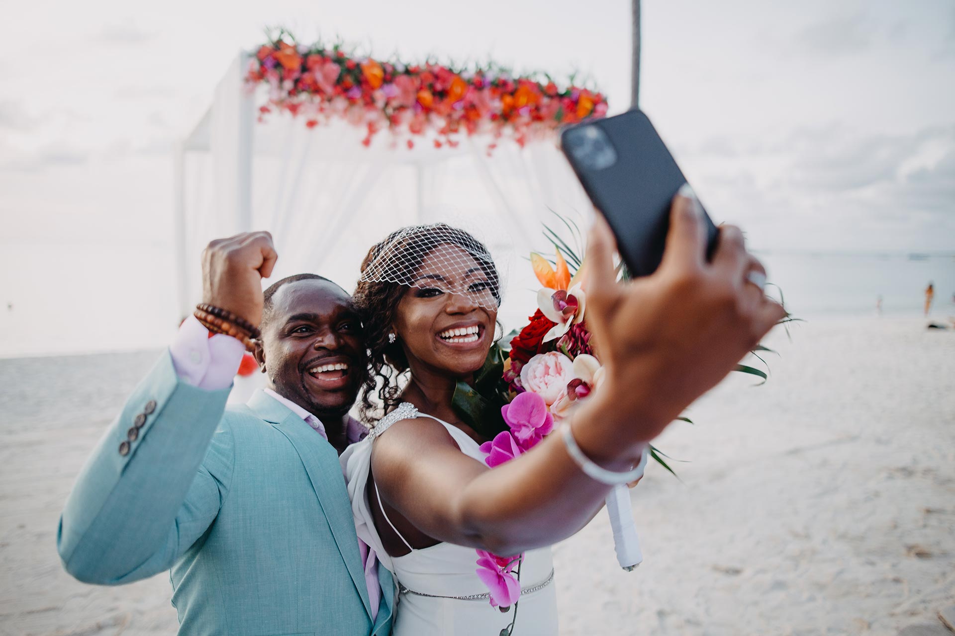 A wedding couple taking a selfie on the beach